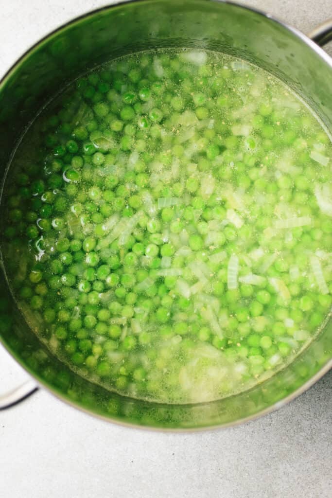 Green peas, onion, garlic, vegetable stock cube in a pot.