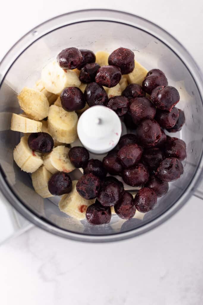 Banana and cherries in a food processor.