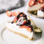 A slice of cheesecake topped with strawberries and chocolate sauce.